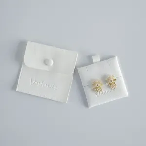 Close-up detail of exquisite flower pearl earrings displayed with white velvet pouch and card.
