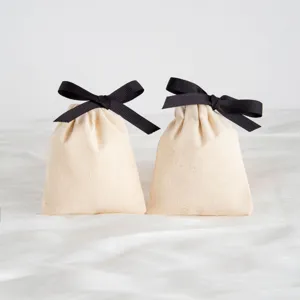 Dettaglio di sacchetto regalo in cotone beige con coulisse e chic fiocco in nastro nero.