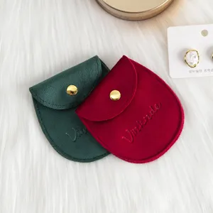 Gros plan détaillé de poches à bijoux en velours avec boutons pression dorés vert et rouge.