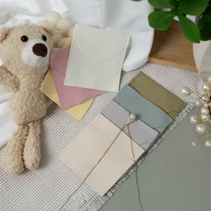 Detailed view of soft flannel envelope jewelry pouches in assorted pastel colors with props.