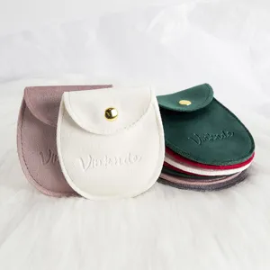 Détail de pochette à bijoux en velours, texture douce et bouton-pression doré pratique.