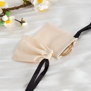 Sacchetti porta gioielli in cotone beige con nastro nero, elegante confezione regalo utile.