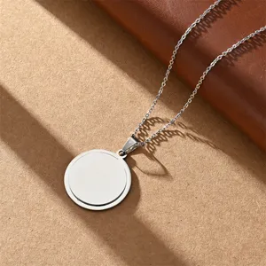Stainless steel blank round pendant necklace with fine chain, minimalist jewelry detail shot.