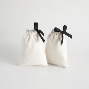 Nahaufnahme des weißen Baumwoll-Kordelzugsacks mit schwarzer Schleife für Geschenke.