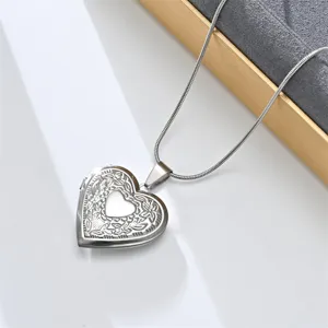 Close-up detail of vintage stainless steel heart locket necklace with floral engraved pattern.