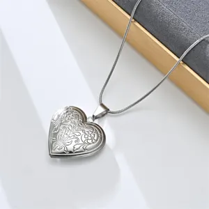 Stainless steel heart locket necklace with vintage floral engraved pendant, jewelry detail view.