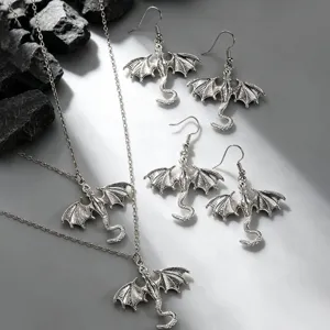 Close-up shot of vintage silver dragon necklace and earrings set, gothic fantasy jewelry detail.