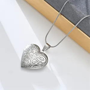 Detail of vintage silver heart locket pendant necklace with intricate floral engraving design.