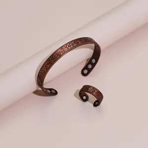 Close-up view of the vintage copper magnetic bracelet and matching floral ring details.