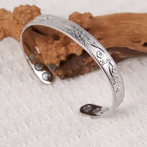 Vintage metal cuff bracelet featuring engraved plum blossoms and inner magnetic stones.