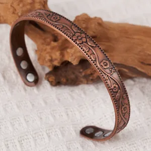 Vintage copper magnetic bracelet detail view showing floral relief engraving and inner therapeutic magnets.