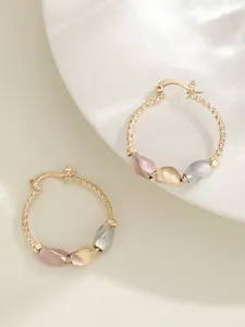 Gedetailleerde close-up van stijlvolle geometrische driekleurige creolen met elegante kralen.