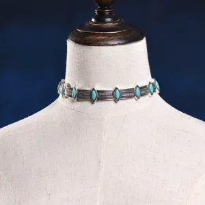 Detail view of a vintage bohemian turquoise alloy choker necklace with intricate tribal carving.