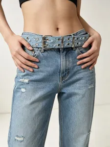 Punk style distressed denim belt detail showing metal double buckle and star eyelet design.