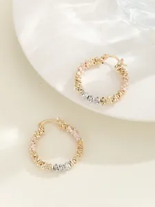 Detailopname van geometrische driekleurige creolen met goud-, roségoud- en zilveren tinten.
