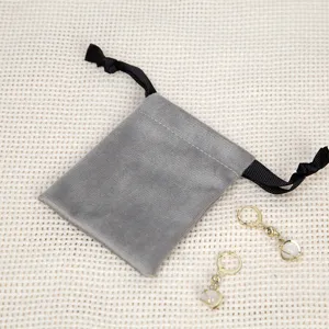 Grauer Samtschmuckbeutel mit eleganten Ohrringen, weiche Aufbewahrung für Accessories.