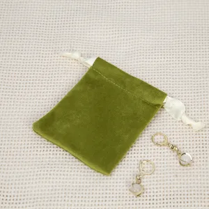 Detailaufnahme eines grünen Samt-Schmuckbeutels mit Kordelzug und eleganten Perlenohrringen.