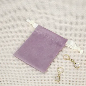Violetter Samt-Schmuckbeutel mit weißer Kordel und eleganten Ohrringen Detailansicht.