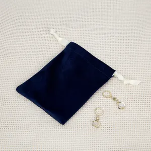 Dunkelblaue Samt Schmuck Beutel mit Kordelzug und kleinen Anhänger Ohrringen Detail Ansicht.