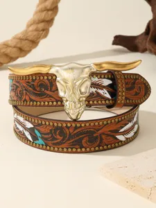 Western leather belt detail showing embossed floral patterns, metal studs, and bull skull buckle.