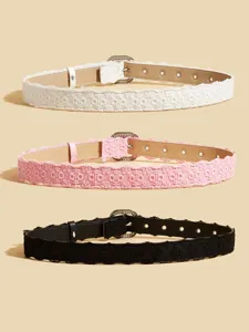 Close-up detail of stylish women lace belts in white, pink and black with sparkling rhinestone buckles.