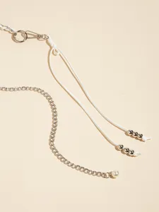 Close-up view of a stylish metal waist chain featuring silver links, white cords, and pearl.