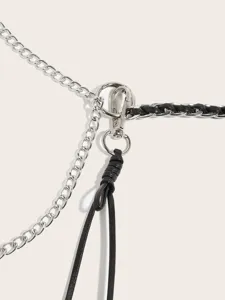 Close-up detail view of stylish metal chain and black leather woven waist belt accessory.