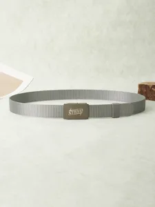 Détail de ceinture en toile tissée grise montrant la boucle en métal avec texte en relief.