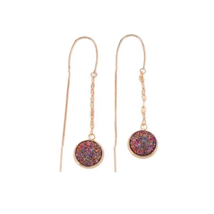 Close-up of long rose gold threader earrings featuring vibrant colorful round glitter pendants.