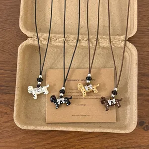 Close-up of cute spotted puppy pendant necklace with bow, delicate beads, and adjustable cord.