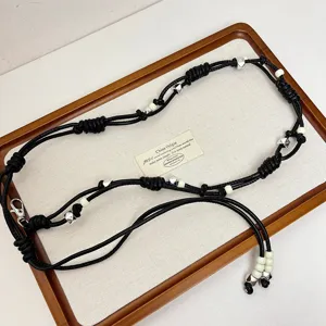 Gedetailleerd overzicht van de zwarte lederen tailleketting met metalen kralen op tray.