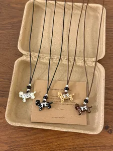 Detailed view of four colorful spotted puppy pendant necklaces with bows in paper box.