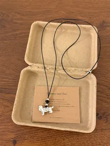 Detailed view of the cute dotted puppy pendant necklace with adjustable black cord and card.