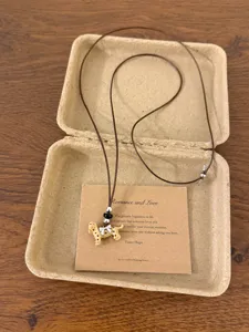 Detailed view of cute spotted puppy pendant necklace with charming bow and beads on card.