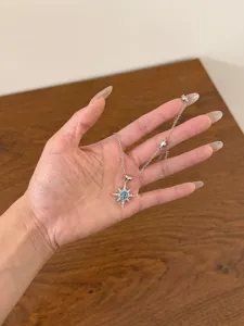 Detailed view of a dainty silver necklace featuring a sparkling blue star pendant and delicate chain.
