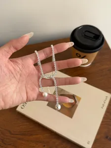 Elegant rhinestone pearl lariat necklace detail, sparkling crystal chain fashion accessory.