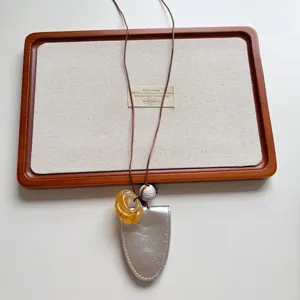 Nahaufnahme Detail der Retro Leder Brillenhalter Halskette mit Bernstein Harzanhänger Perle.