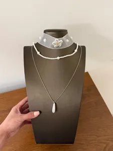 Primo piano dettagliato della collana a strati con choker di perle e ciondolo a goccia.