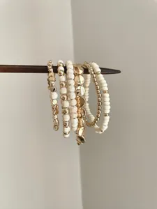 Bohemian multi-layer beaded bracelet detail, retro gold and white stacking accessory.