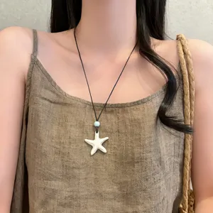 Primo piano dettagliato di una collana con ciondolo a stella chic e cordino nero.