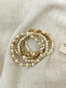Detailed close-up of multi-layer boho beaded bracelets with gold and white stone beads.