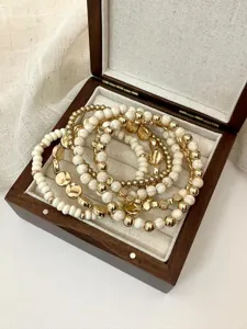 Detailed closeup of bohemian multi-layer beaded bracelet with white stone and gold metal beads.