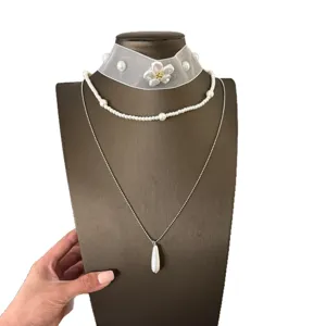 Vista dettagliata della collana a strati con perle e pendente a goccia, design elegante.