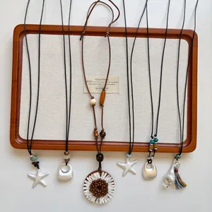 Vista dettagliata di lunghe collane con ciondoli in stile boho con vari motivi geometrici e floreali.