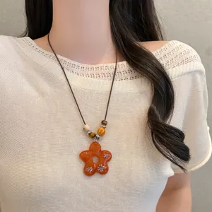 Retro sweet-cool beaded long sweater chain with a striking orange flower pendant detail.