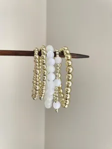 Detailed view of vintage multi-layer stacked beaded bracelets with gold and white beads.