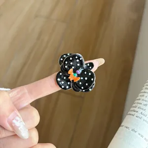 Detail shot of a black and white polka dot flower ring, handmade enamel open ring design.