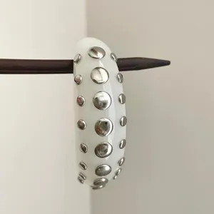 Detailed view of white resin studded bangle bracelet, silver metal dots accessory close up.