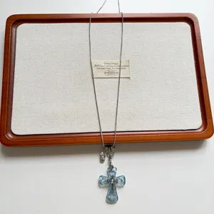 Detailed view of a vintage light blue glass cross pendant long sweater chain with silver chain.