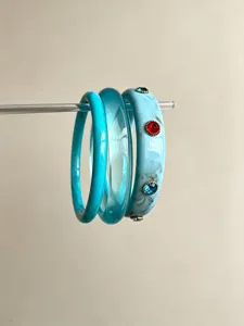 Detailed close-up of fashionable layered resin bangles, featuring marble pattern and rhinestones.